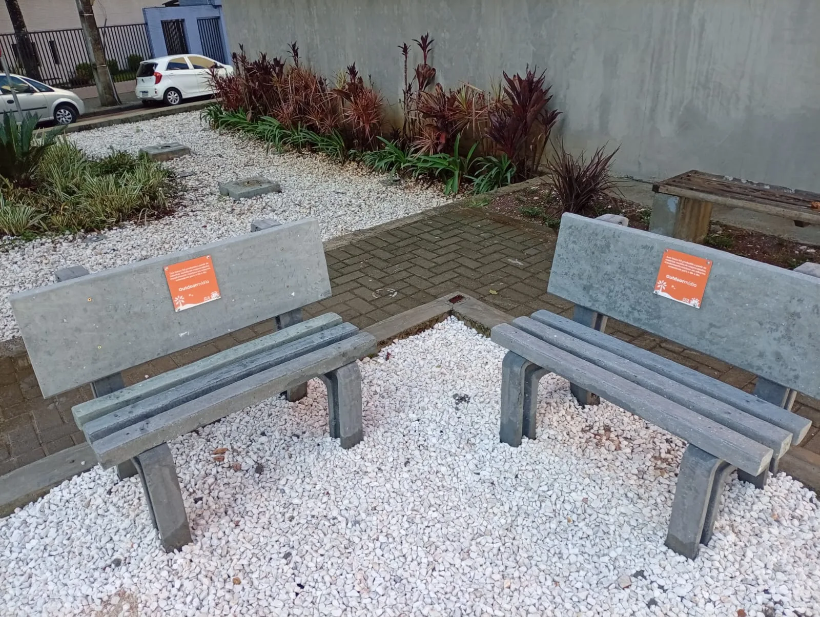 Bancos produzidos com lona publicitária reciclada instalados em praça, com placa da Outdoormídia