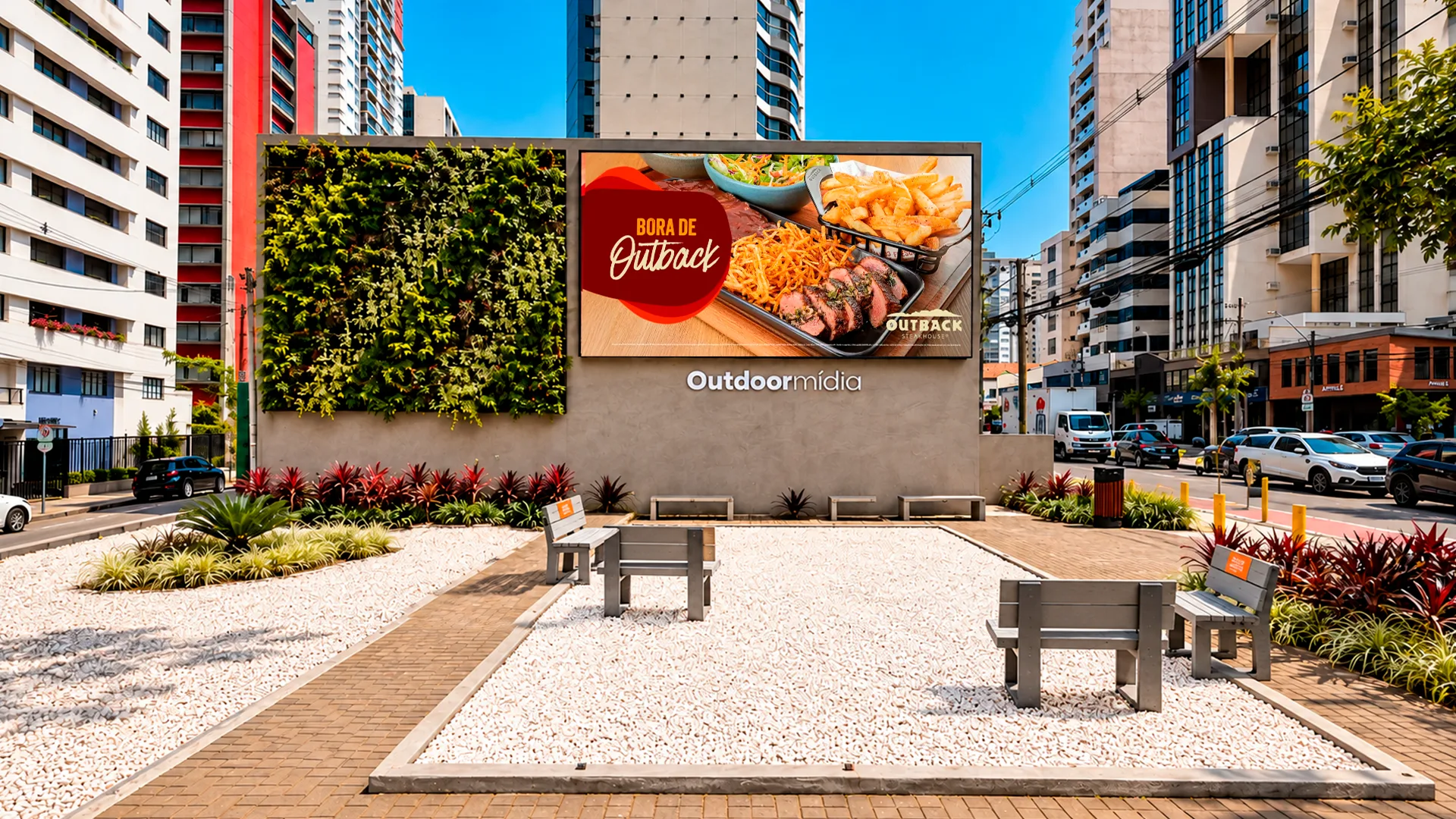 Outdoormídia 的 LED 屏幕正在播放 Outback 的广告，旁边是一面垂直花园，位于库里蒂巴楼宇之间一座设有长椅与绿化的广场上
