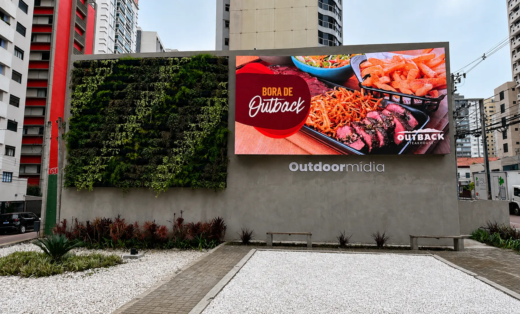 Painel de LED da Outdoormídia ao lado de jardim vertical, em muro de esquina no Batel, em Curitiba