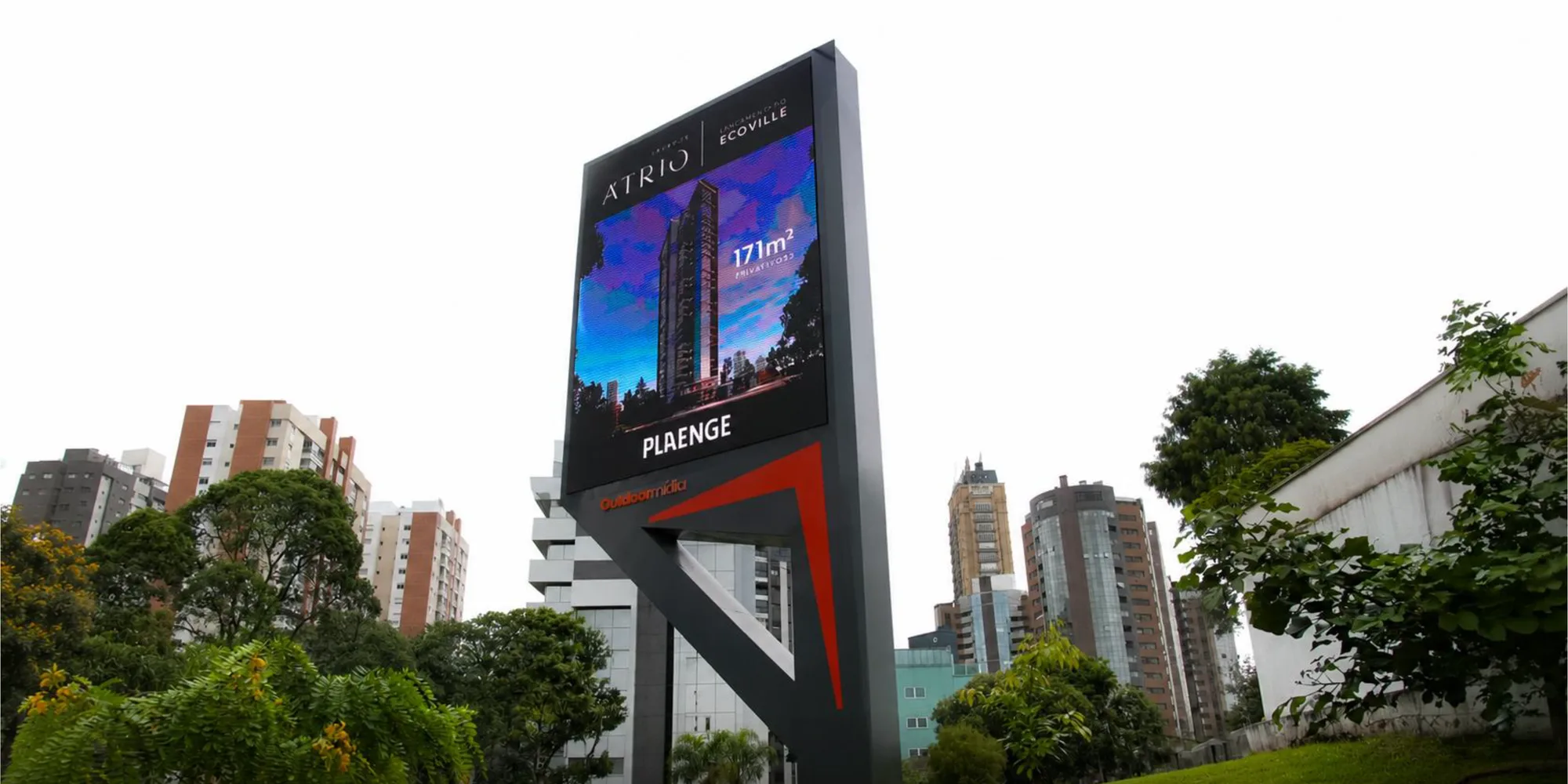 Estrutura vertical com painel digital e base iluminada em desenho próprio, em avenida de prédios altos