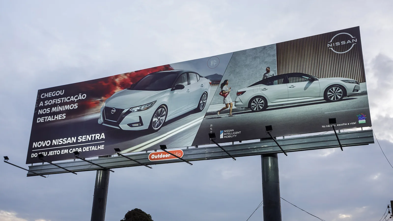 Painel Super Poster estático da Outdoormídia com campanha do Novo Nissan Sentra, sobre dois postes à beira de via