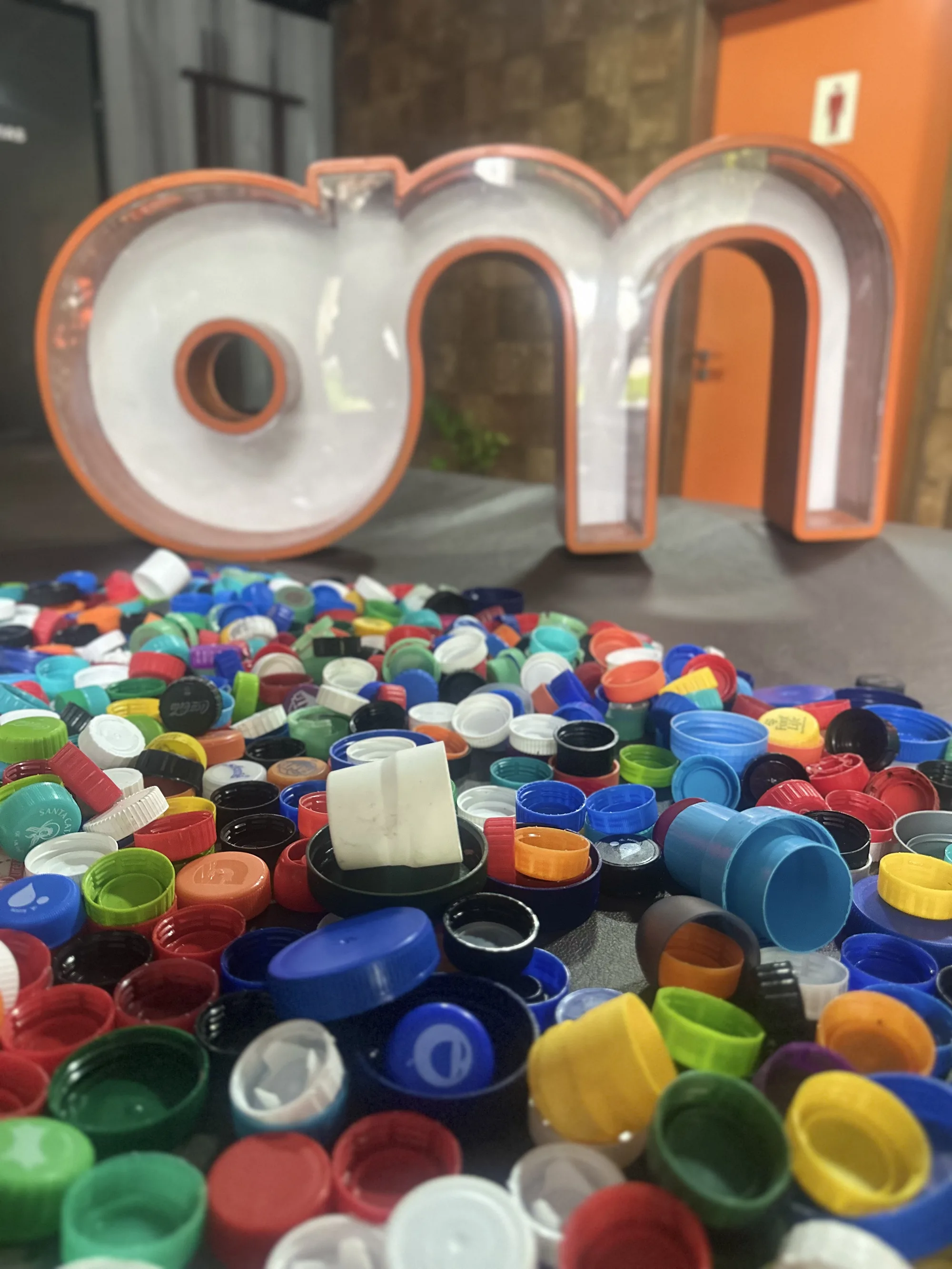 Tampinhas plásticas coloridas arrecadadas na recepção da Outdoormídia